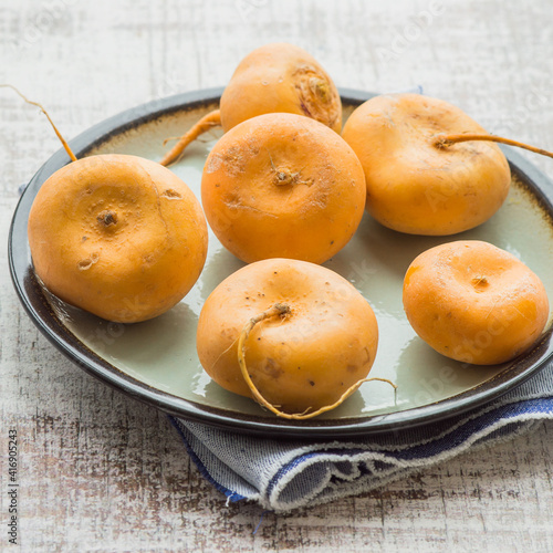 Ripe yellow turnips on a round ceramic plate on an old table. Russian kitchen. Selective focus.