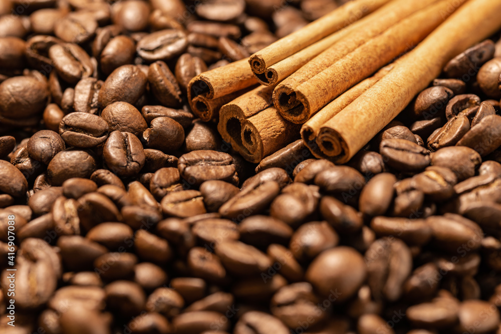 Cinnamon sticks on a background of freshly roasted coffee beans. Coffee beans texture Cinnamon sticks on a background of freshly roasted coffee beans. Coffee beans texture
