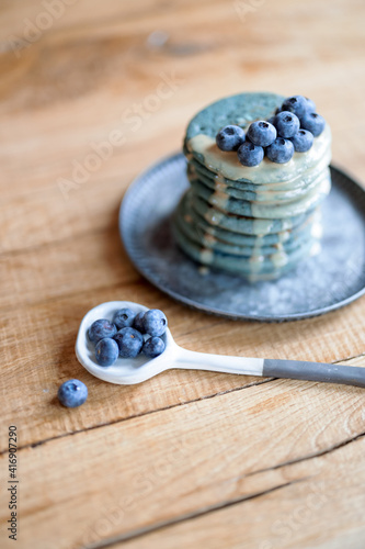 Blue american pancakes decorated with blueberry and caramel souse on vintage plate on wood table. Homemade tasty food. Celebration of Shrovetide.
