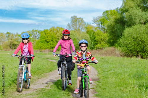 Happy mother and kids on bikes cycling outdoors in park, active family sport  and fitness together
