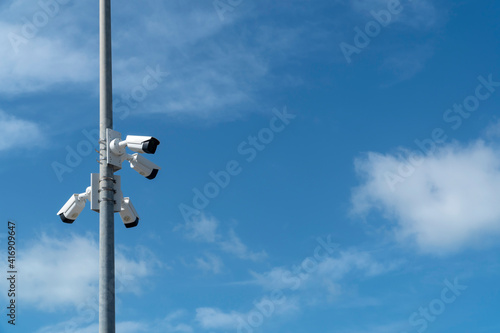 Security systems and alarm technology concept: Many CCTV cameras hanging on a outdoor pol and recording. Digital surveillance. High safety and protection cam and video. Blue sky with copy space.