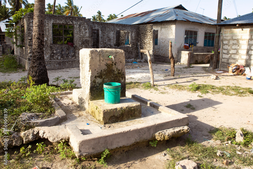 Drinking water supply, well in african village. Plastic container under the tap. Problem with access to the water in africa. Drinking water supply, well in african village. Plastic container under the tap. Problem with access to the water in africa.