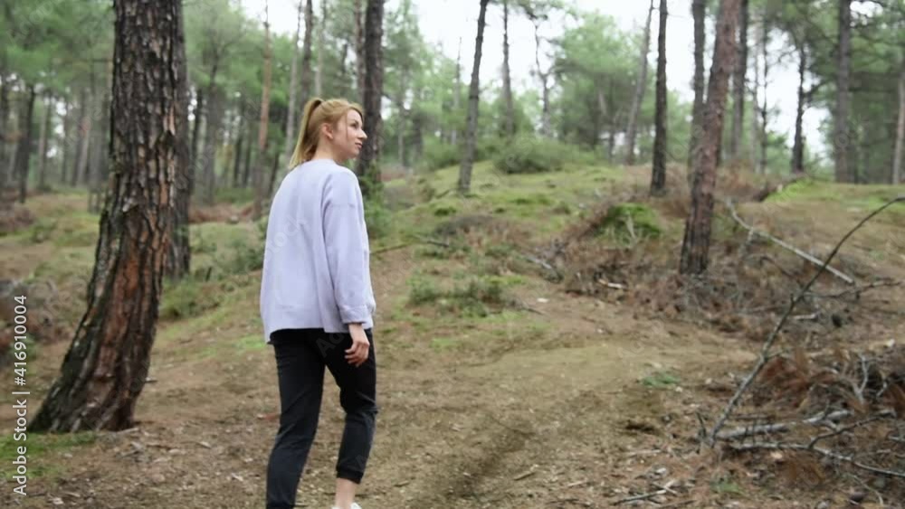 Young beautiful woman walking through a pathway in forest with soft natural lighting. Young beautiful woman walking through a pathway in forest with soft natural lighting.