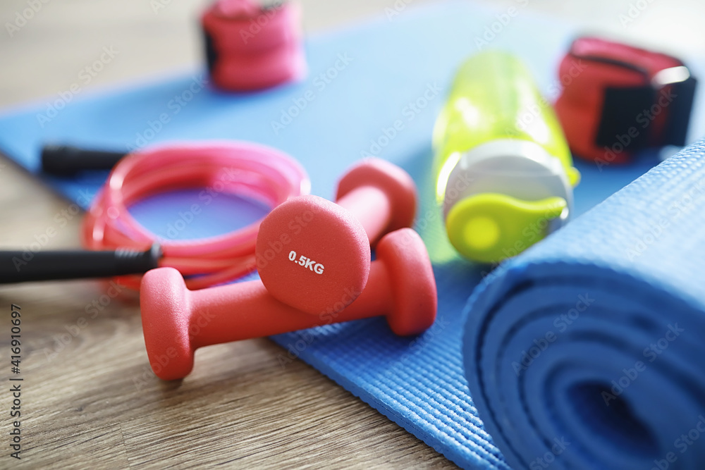 Sport and healthy lifestyle. Accessories for sports. Yoga mat dumbbell and jump rope. Sports background home exercises concept. Sport and healthy lifestyle. Accessories for sports. Yoga mat dumbbell and jump rope. Sports background home exercises concept.