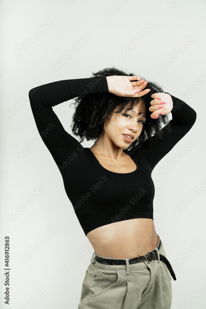 Portrait of a smiling stylish Afro-looking woman posing in a photo studio on a white background. hands near the head looking at the camera. copy space. Portrait of a smiling stylish Afro-looking woman posing in a photo studio on a white background. hands near the head looking at the camera. copy space.