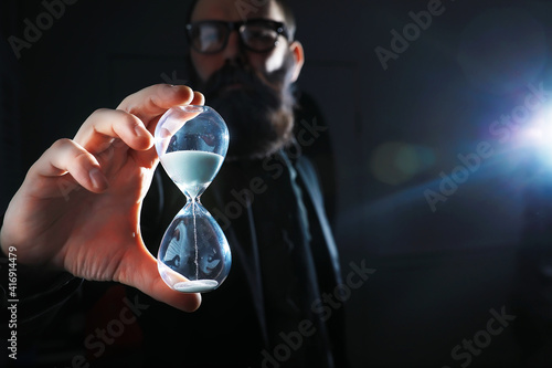 A bearded man in a suit holds an object in his hand. Concept of time and ideas. Aspiration and development.