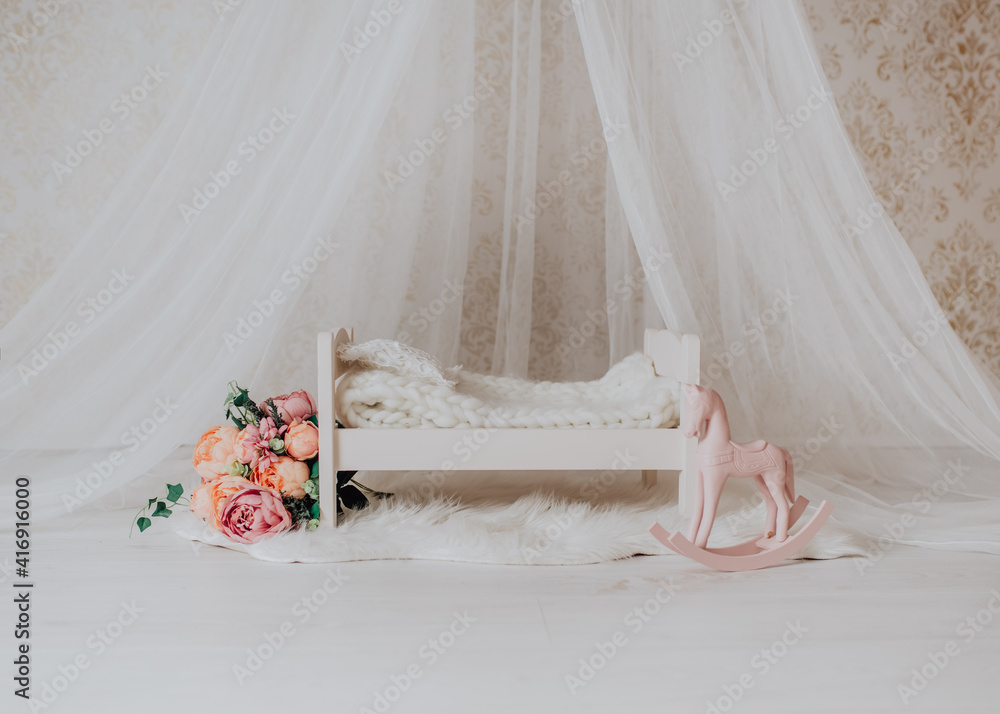 Newborn baby girl bed in a photo studio with flowers and a rocking horse Stock Photo Adobe Stock