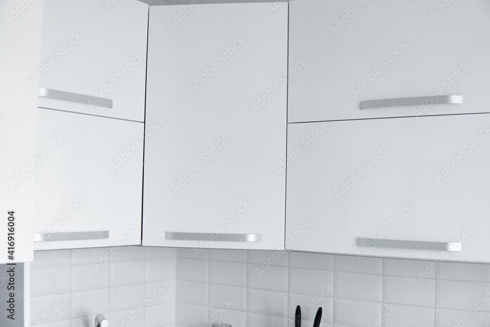 White lacquered kitchen facades on a comfortable kitchen. Modern white kitchen clean interior design. White lacquered kitchen facades on a comfortable kitchen. Modern white kitchen clean interior design.