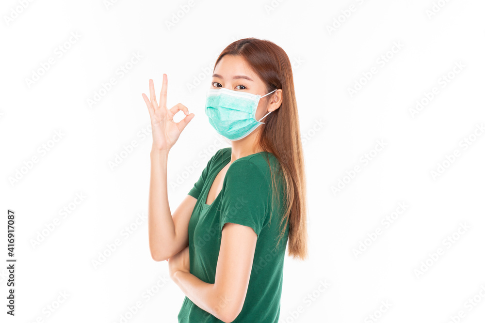 Young Asian teenage girl on white background. Casual Asian woman wearing surgical mask, corona virus (Covid-19) prevention. Casual Asian woman wearing green t-shirt over white background. Young Asian teenage girl on white background. Casual Asian woman wearing surgical mask, corona virus (Covid-19) prevention. Casual Asian woman wearing green t-shirt over white background.
