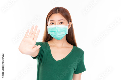 Young Asian teenage girl on white background. Casual Asian woman wearing surgical mask, corona virus (Covid-19) prevention. Casual Asian woman wearing green t-shirt over white background.