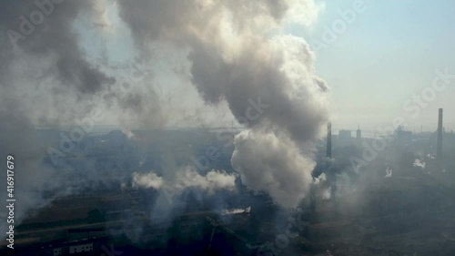 Drone fly around toxic enterprise chimneys tubing against the sky background release smoke. Factory pollutes environment. Aerial view. Ecology disaster. Azovstal. Mariupol, Ukraine photo