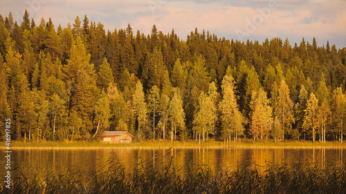 small red house at lake in nordic autumn landscape