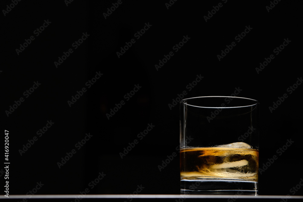 A glass of whiskey with ice on a white marble and black background. With copy space for your text.