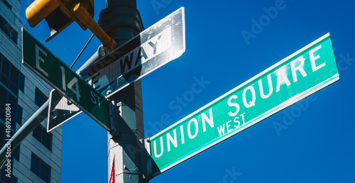 Street sign of Union Square and East 14 St with skylines in background.- New York, USA photo