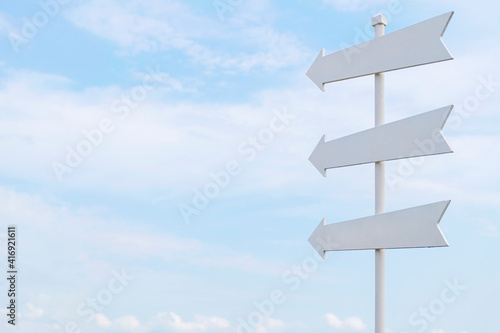White painted wooden sign with an arrow pointing out on sky