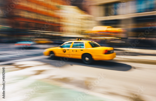 New York City - March 20, 2017 : Yellow taxi cab speeds down in a New York City Street. Shot with long shutter speed for intentional motion blur.