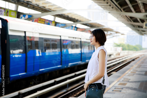 Asian young short hair woman waiting for arriving train on platform