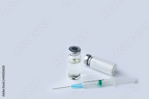 Vaccine vial, medicine drug bottles and syringe injection on a white background. Vaccination, immunization, treatment to Covid-19. Close-up. Copy space.