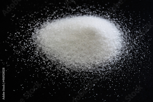 heap of white sugar in black background