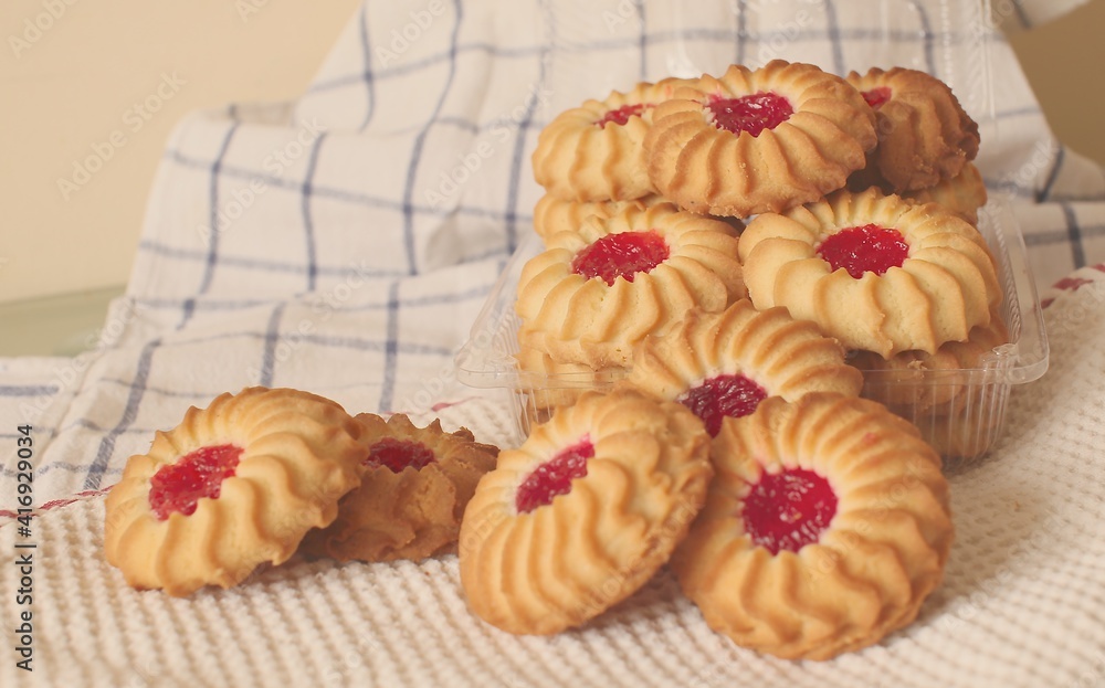 sand cookies with jam in the middle on a napkin and in a plastic box