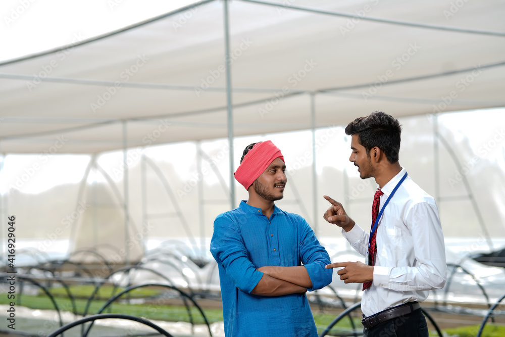 Obraz premium Young indian agronomist discuss with farmer at greenhouse