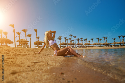 Young fashion woman sitting on the beach shore