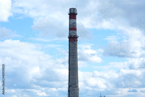 Industrial chimney for an industrial organization. Chimney engineering system on a background of blue sky with clouds.