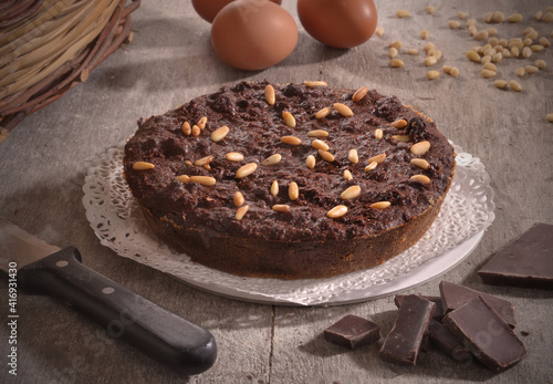 Chocolate nuts cake on rustic kitchen and ingredients.