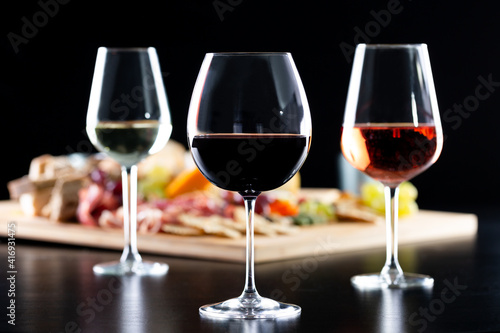 Glasses of red, white and rose wine as foreground over a delicatessen table in the background