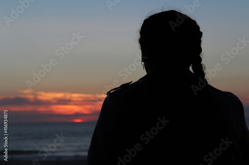 Silhouette of a person looking at the sunset on the ocean 