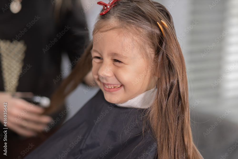 hairdressing salon. Hairdresser girl doing hairstyle to a little girl