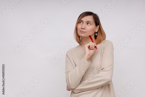 Young pensive woman on a white background with a pen in her hands