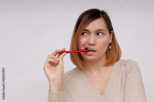 Young pensive woman on a white background with a pen in her hands