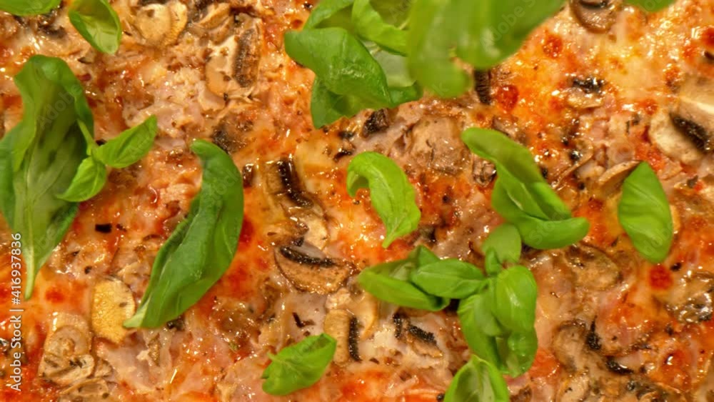 Super Slow Motion Shot of Basil Leafs Falling on Fresh Pizza at 1000 fps. Top Shot with Camera Motion. Super Slow Motion Shot of Basil Leafs Falling on Fresh Pizza at 1000 fps. Top Shot with Camera Motion.
