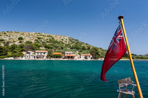 Tiny hamlet inhabited only in Summer on Otok Lavsa in the Kornati National Park, Croatia: British Red Ensign flying on a yacht in the foreground photo
