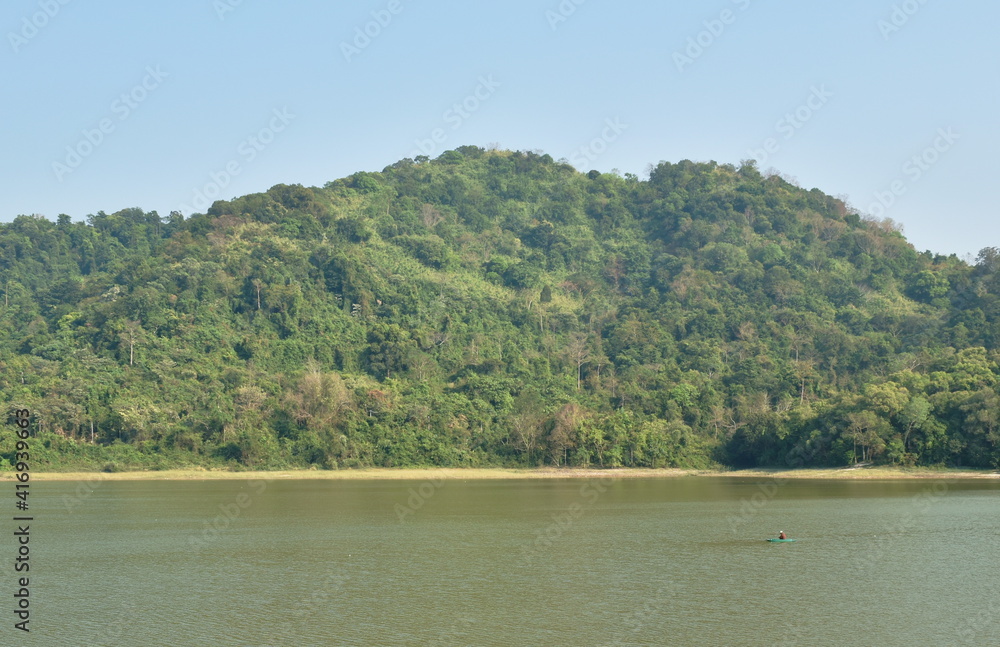 wooden fishery row boat floating on lake with mountain background wooden fishery row boat floating on lake with mountain background