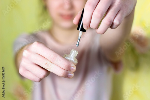 The girl paints her nails with a shiny varnish. Blurry.