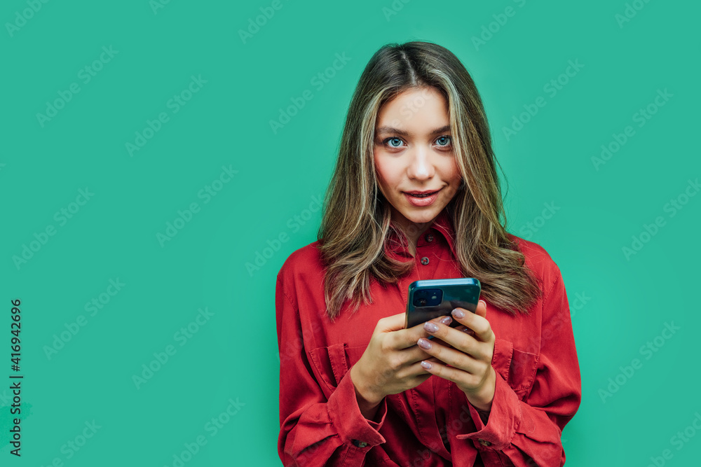 Attractive girl with a phone in her hands, she is interested in looking at the camera, a place for text Attractive girl with a phone in her hands, she is interested in looking at the camera, a place for text