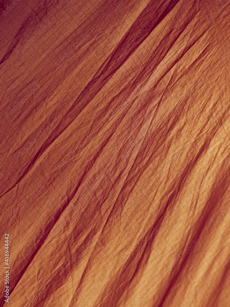 Naklejka premium Orange abstract wrinkled fabric background with copy space, view from above