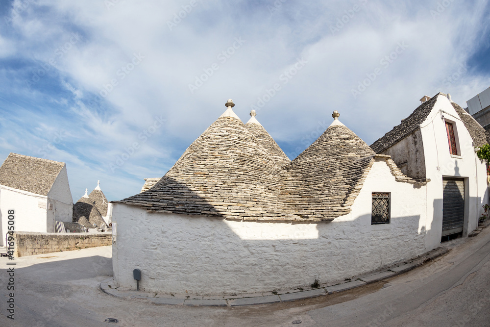 Typical street in Alberobello, a Trulei village, with white houses with a tapered stone roof. Photo taken with a fisheye lens.