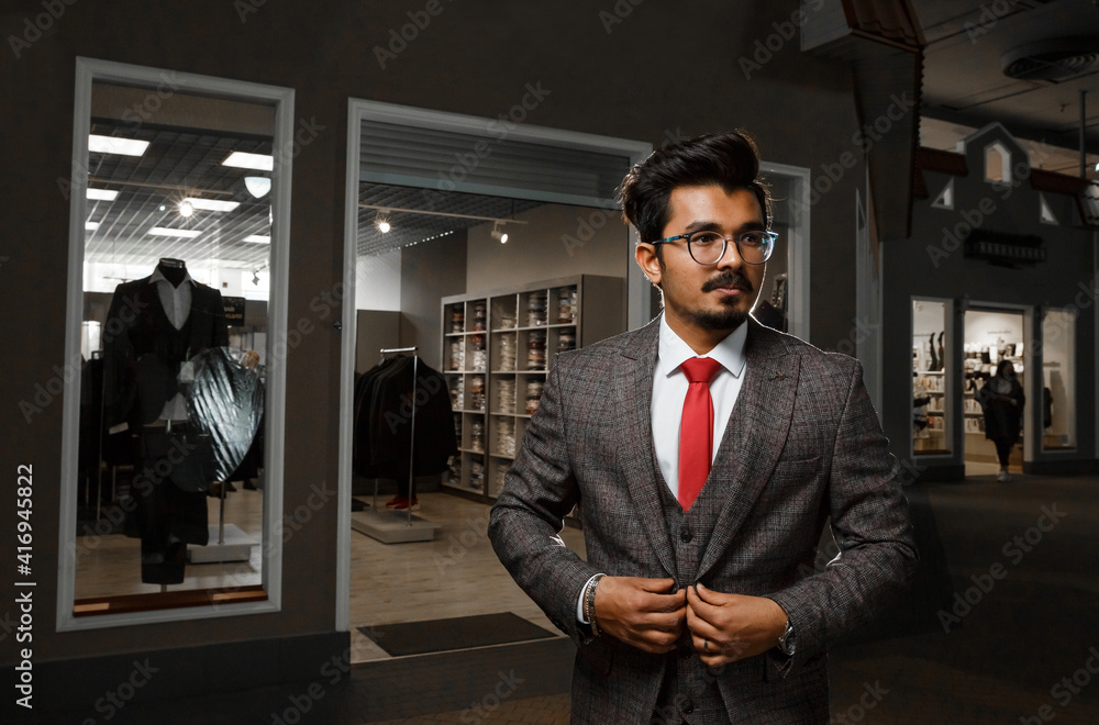 Confident elegant handsome young man standing in front of an expensive boutique in a handsome suit. Confident elegant handsome young man standing in front of an expensive boutique in a handsome suit.