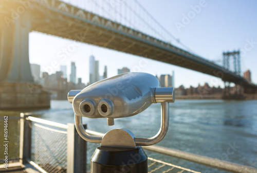View of Manhattan bridge and New York City with a coin operated telescope binoculars viewer for tourists.