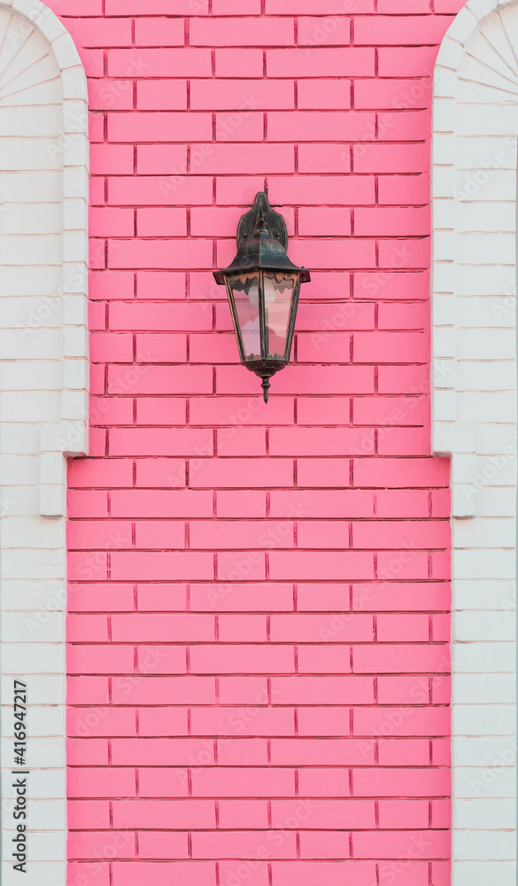 Decor element on symmetrical building facade with lamp, vintage retro lantern on pink white brick wall with texture, loft style architectural decorative background