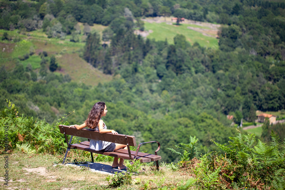 Chica adolescente disfrutando del paisaje de montaña desde un banco Chica adolescente disfrutando del paisaje de montaña desde un banco