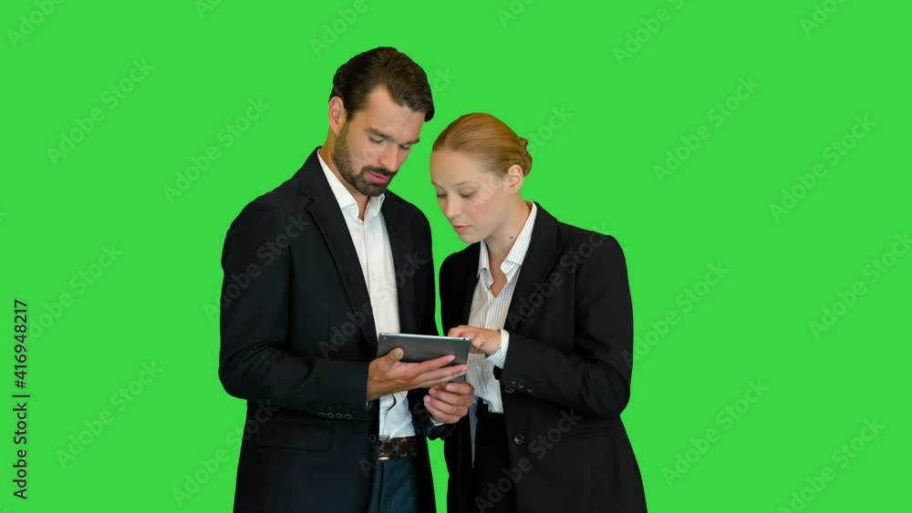 Beautiful young business woman and handsome businessman in formal suits are using a digital tablet on a Green Screen, Chroma Key. Beautiful young business woman and handsome businessman in formal suits are using a digital tablet on a Green Screen, Chroma Key.