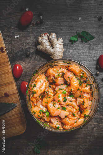 Fotografia Raw marinated chicken meat with garlic, ginger and teriyaki sauce in a glass bow