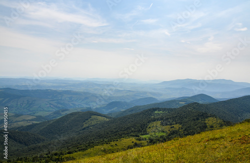 Aerial view of scenic rolling countryside covered green forest at summer morning. Carpathian Mountains, Ukraine