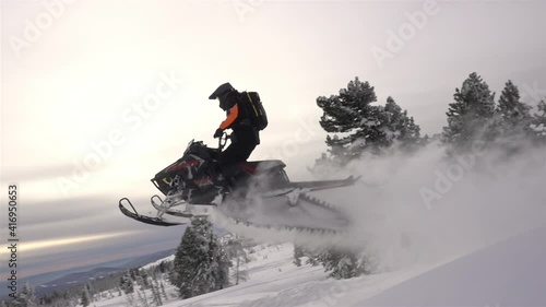 SLOW MO: video footage of jumping snowmobilers at sunset. the snowmobile flies through the air and creates large and beautiful swirls of snow. ProRes 422. HD 500fps