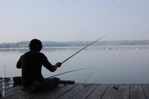 the silhouette of a man fishing in the wide sea