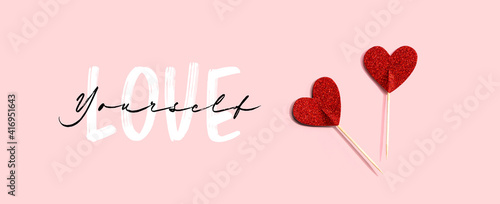 Love Yourself message with red glitter heart picks - flat lay
